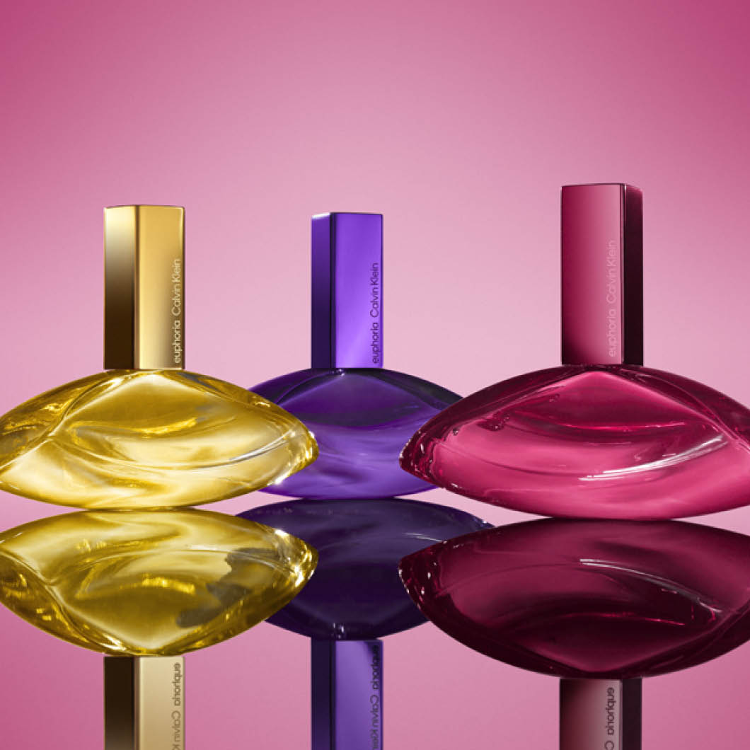 Tre Calvin Klein parfymflaskor i olika färger mot rosa bakgrund.